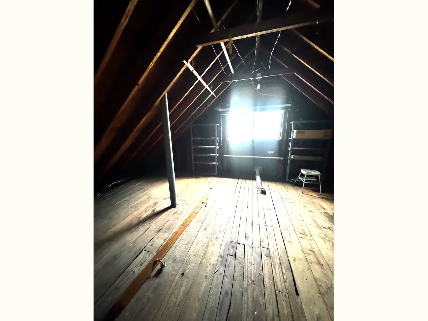 The same attic after — completely cleared, with bare floorboards and empty shelving