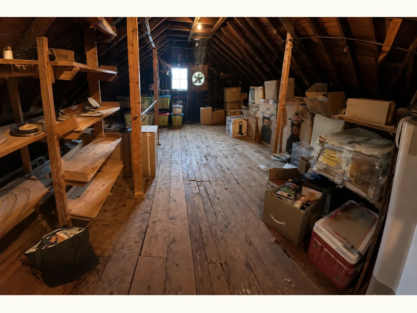 Attic before organizing — boxes, bins and stored belongings stacked along both walls and across the floor